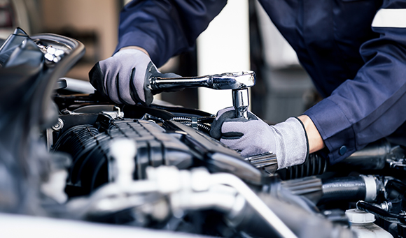 a man using a wrench to screw in a part into an engine of a car